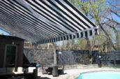 a building with a striped awning overlooking a pool