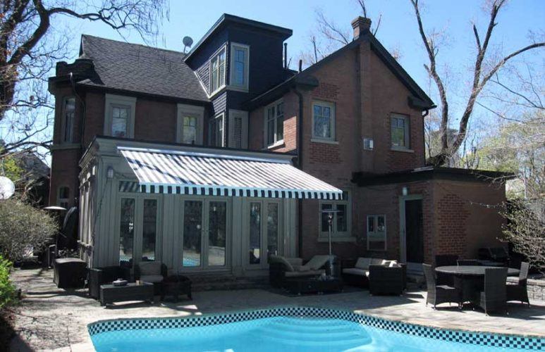 a building with a striped awning overlooking a pool